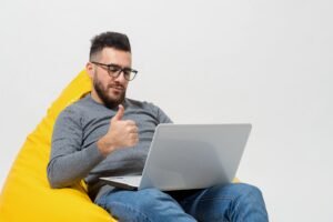 Man giving a thumbs-up while working on a laptop, representing digital marketing success and productivity.